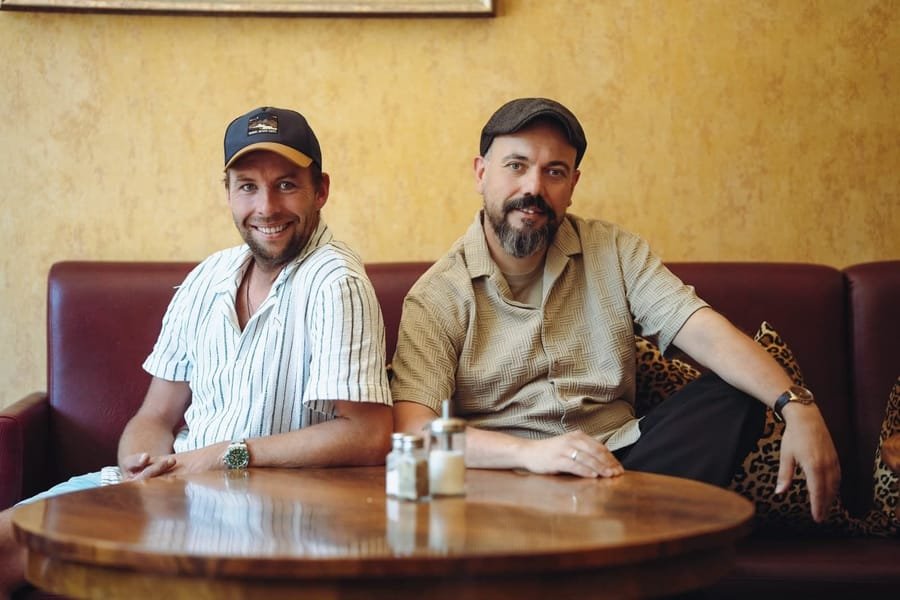 Michi Weinmann und Toni Schreiner sitzen an einem Tisch im Studio